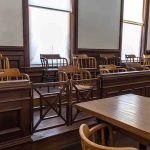 Juror Kept in Safehouse- ATTACKED For Being Republican Empty jury box in a courtroom with wooden chairs