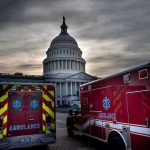 Ambulances parked near a domed government building at dusk