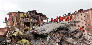 Rescue workers in orange uniforms on a collapsed building site after an earthquake