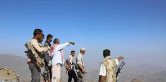 Group of armed men standing on a rocky mountain ridge