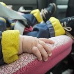 baby hand resting on a pink car seat