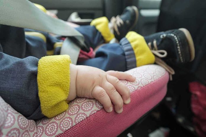 baby hand resting on a pink car seat