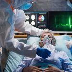 Patient on hospital bed with oxygen mask and medical staff in protective gear
