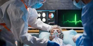 Patient on hospital bed with oxygen mask and medical staff in protective gear