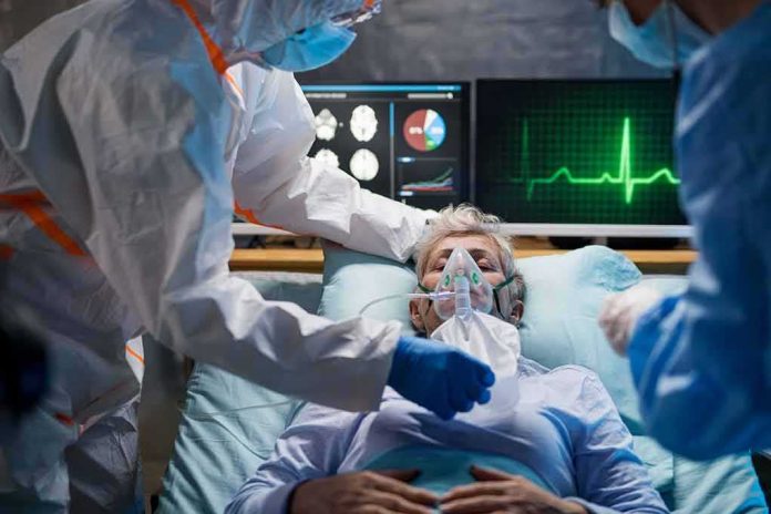Patient on hospital bed with oxygen mask and medical staff in protective gear