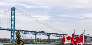 Suspension bridge over a river with Canadian flags in the foreground
