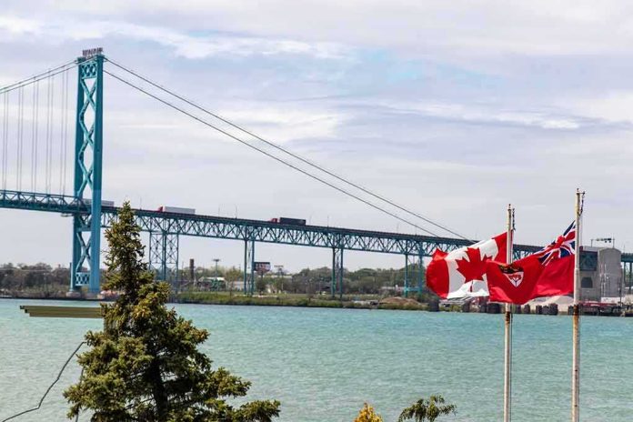 Suspension bridge over a river with Canadian flags in the foreground