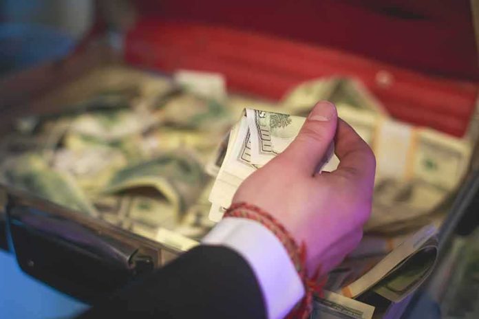 Hand holding cash over an open briefcase filled with money