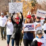 Group of protesters marching with political signs and hats