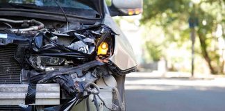 Front of a car with severe collision damage and exposed headlight