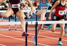 Female athletes clearing hurdles on a track