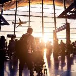 Airport terminal crowd at sunset with airplane silhouette outside