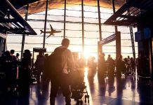 Airport terminal crowd at sunset with airplane silhouette outside