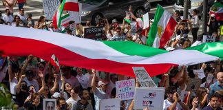 Protest crowd with flags and signs; Seyed Ebrahim Raisi, La Parka, Brian Robiskie, Philly Brown, Miguel Francisco Barragán Andrade present