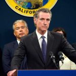 Man in suit at podium with microphones during press conference