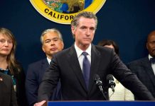 Man in suit at podium with microphones during press conference