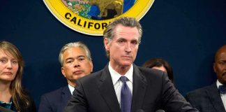 Man in suit at podium with microphones during press conference
