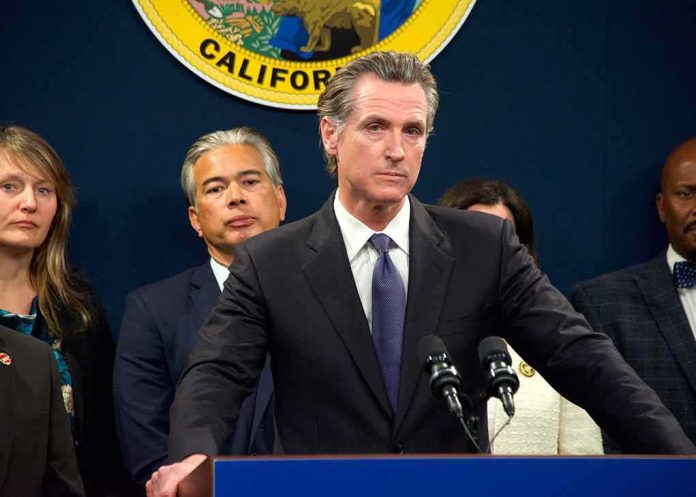shutterstock_2259638251 Man in suit at podium with microphones during press conference
