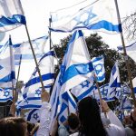 Crowd waving Israeli flags outdoors