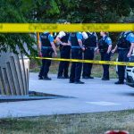 Campus Bomb Note Triggers Terror Bust police officers stand behind caution tape at a park scene
