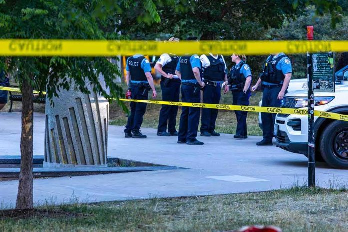 shutterstock_2325984679-1 police officers stand behind caution tape at a park scene