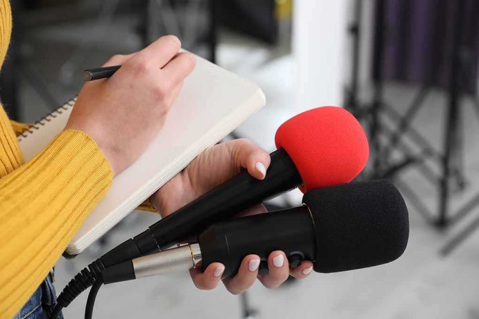 shutterstock_2431198207-3 Journalist holding two microphones while writing in a notebook