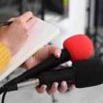 WNBA Star Lights Fuse — White House Jumps In Journalist holding two microphones while writing in a notebook