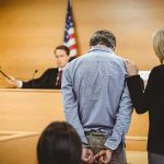 Disgraced Tate Bothers ARRESTED – Extradition Looms! Defendant in handcuffs stands before a judge in a courtroom