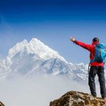 Hiker IMPALED – Still Walks Ten Miles to Hospital Hiker with arms raised facing snowy mountain peak