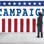 Dem Senator CAUGHT – Splurging Campaign Funds! Man in suit writing on large campaign banner with stars and stripes