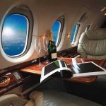 DOJ Targets Newsom’s Donor-Funded Jet-Setting private jet cabin with leather seat, champagne and magazine on table