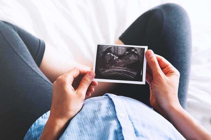 Person holding an ultrasound photo over a pregnant belly