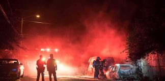 Firefighters and police at a nighttime car fire scene