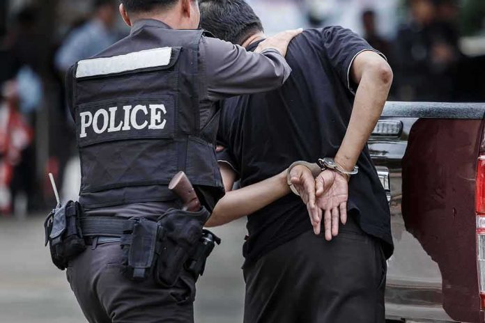 Police officer escorting handcuffed man to a vehicle