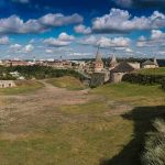 Medieval stone castle with towers on a grassy hill under a cloudy sky