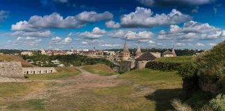 Medieval stone castle with towers on a grassy hill under a cloudy sky