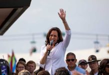 Kamala Harris waves while speaking to a crowd with a microphone
