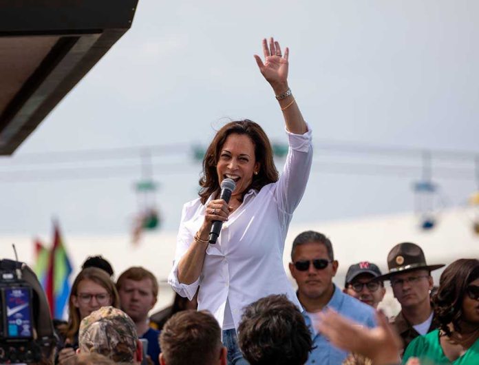 147618444 Kamala Harris waves while speaking to a crowd with a microphone
