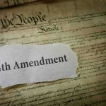 Fourth Amendment text on torn paper over the U.S. Constitution