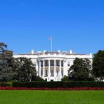 The White House facade with flag and gardens