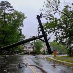 Fallen utility poles blocking a wet suburban street