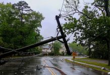 Fallen utility poles blocking a wet suburban street