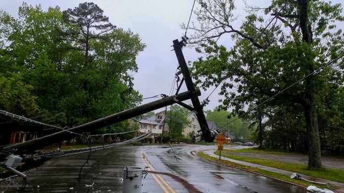 shutterstock_1093124054 Fallen utility poles blocking a wet suburban street
