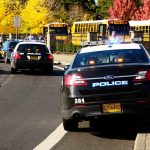 School Hikes Turns DEADLY – Student Picks Up Unexploded Missile Police cars with lights on near school buses on a city street