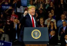 Donald Trump speaking at a rally behind a presidential podium