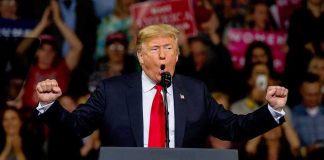 Rally Mayhem Erupts in Texas Donald Trump speaking at a rally podium with arms raised