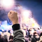 Raised fist in front of a large crowd at night