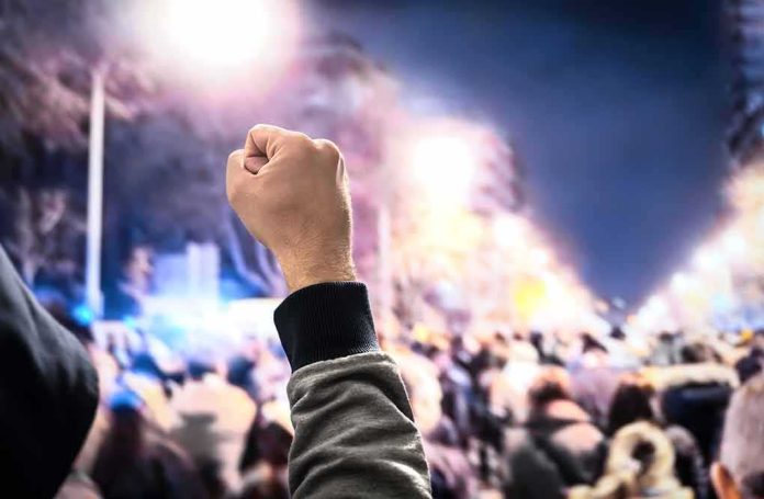Raised fist in front of a large crowd at night