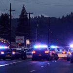 Senate Candidate in Custody After Armed Standoff Police cars with flashing lights block a road at night