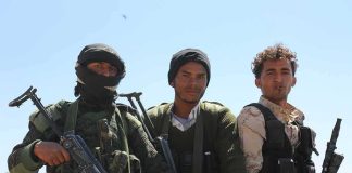 Three armed men standing outdoors